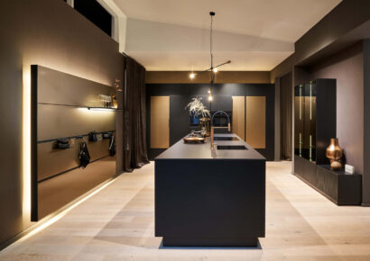 Industrial Küche von Häcker mit Kochinsel, dunklen Fronten und modernem Lichtkonzept